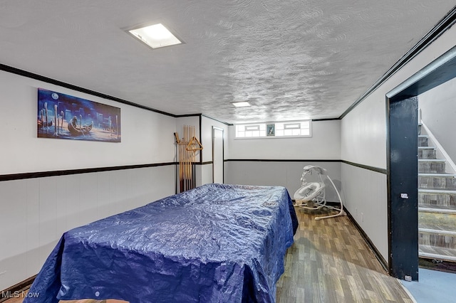 bedroom featuring dark hardwood / wood-style floors, ornamental molding, and a textured ceiling