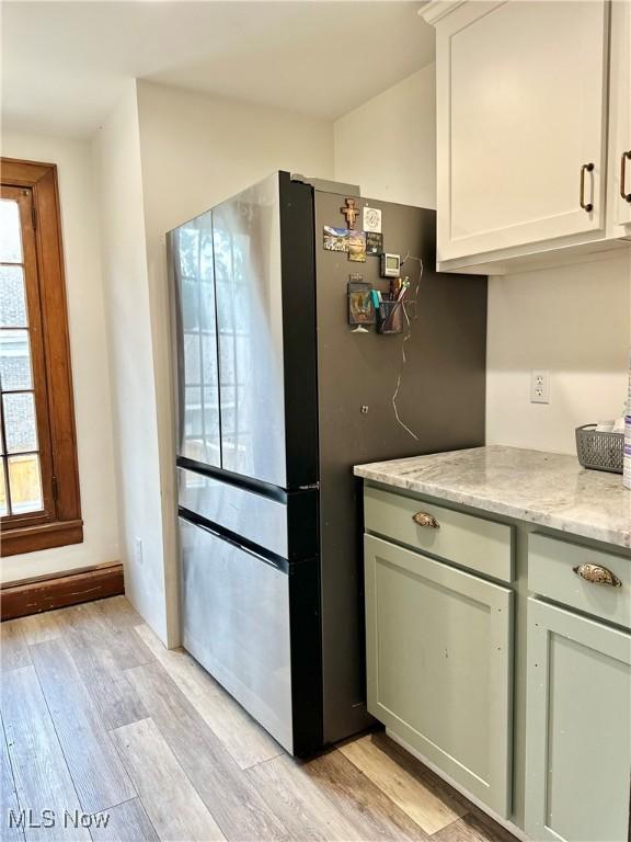 kitchen featuring freestanding refrigerator, light wood-style flooring, and light stone countertops