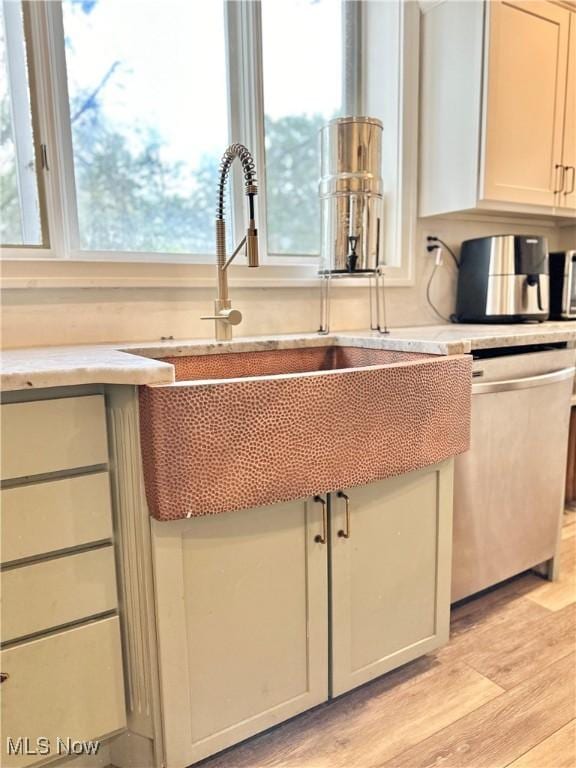 kitchen featuring dishwasher, light wood-style flooring, and a sink