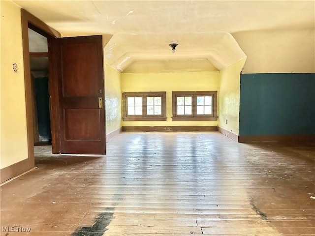 unfurnished living room featuring baseboards, vaulted ceiling, and wood-type flooring