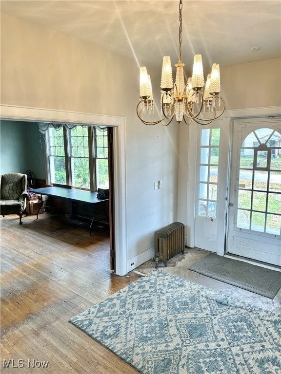 doorway with a healthy amount of sunlight, radiator, an inviting chandelier, and hardwood / wood-style flooring