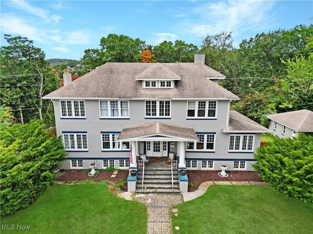 view of front facade with stucco siding, roof with shingles, french doors, a front yard, and a chimney
