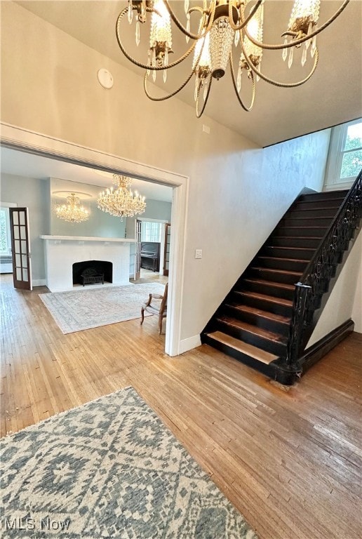 stairs with hardwood / wood-style floors and a chandelier