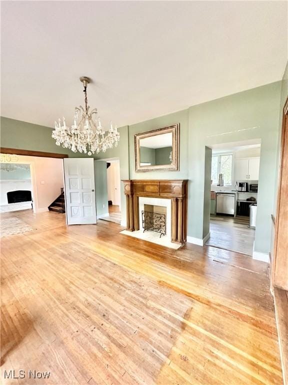 unfurnished living room with hardwood / wood-style flooring, a fireplace with flush hearth, and a chandelier