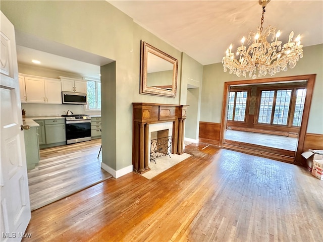 unfurnished living room featuring an inviting chandelier, light wood-type flooring, and a healthy amount of sunlight