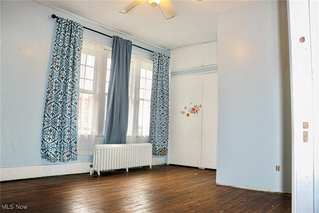 empty room featuring radiator heating unit, ceiling fan, and dark hardwood / wood-style floors