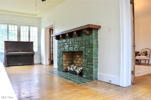 unfurnished living room featuring ceiling fan, a stone fireplace, and hardwood / wood-style floors