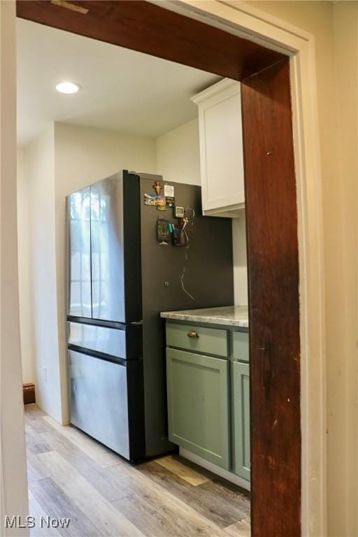 kitchen with green cabinets, light countertops, light wood-style flooring, white cabinetry, and freestanding refrigerator