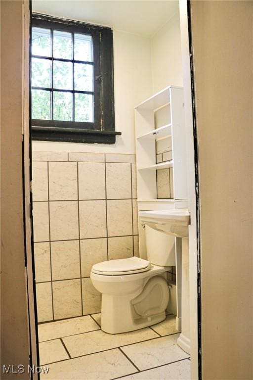 bathroom with tile walls, toilet, and tile patterned flooring