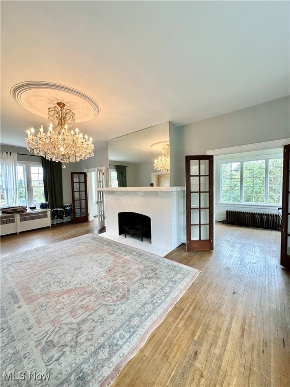 unfurnished living room featuring radiator, a chandelier, and hardwood / wood-style floors