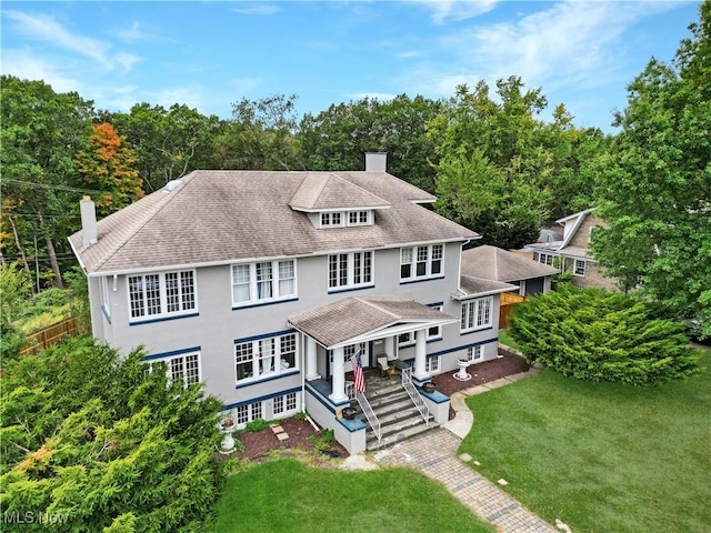 american foursquare style home with a front yard, stucco siding, and a chimney