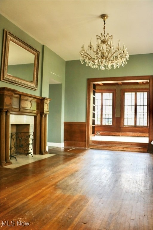 unfurnished living room featuring wood-type flooring and a notable chandelier