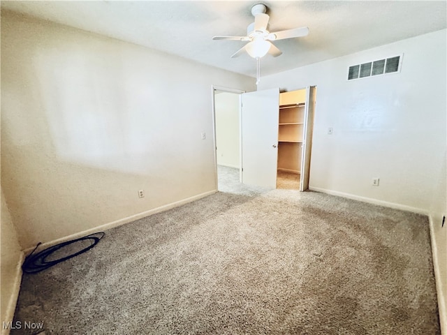 unfurnished bedroom with carpet, ceiling fan, a spacious closet, and a closet