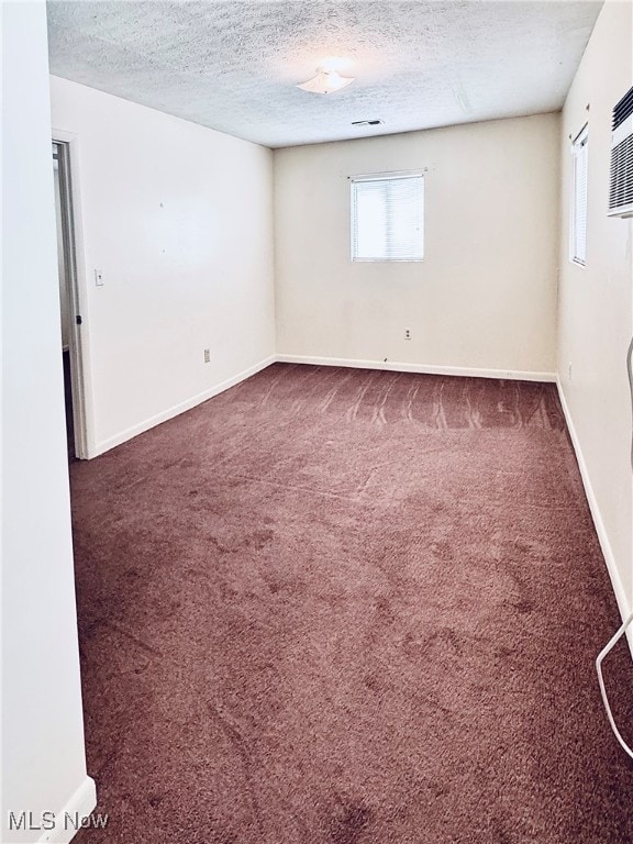 spare room with dark carpet and a textured ceiling