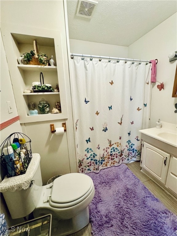 bathroom with vanity, wood-type flooring, a textured ceiling, and toilet