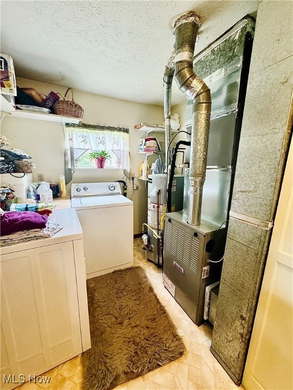 clothes washing area featuring washing machine and clothes dryer, water heater, and a textured ceiling