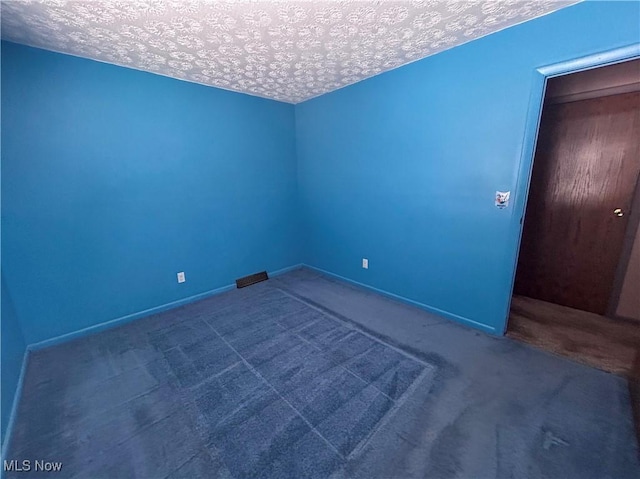 spare room featuring carpet and a textured ceiling