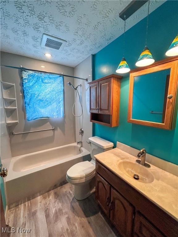 full bathroom featuring bathing tub / shower combination, wood-type flooring, a textured ceiling, toilet, and vanity