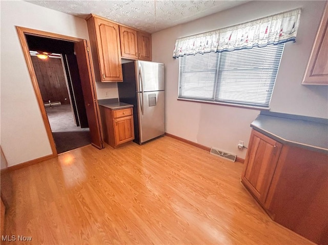 kitchen featuring light wood-type flooring, stainless steel fridge, a textured ceiling, and ceiling fan