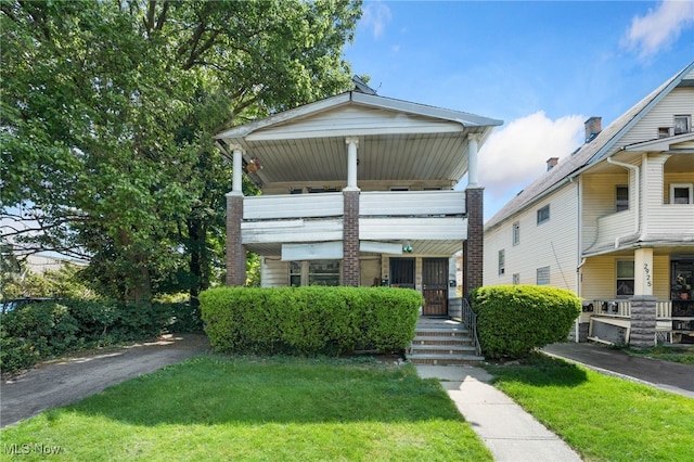 view of front of house with a balcony and a front lawn