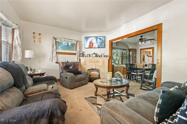 living area featuring ceiling fan, a fireplace, and carpet flooring