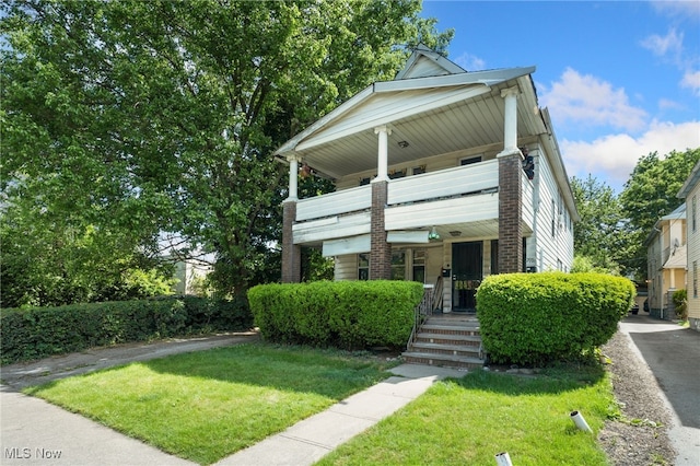 view of front of property with a balcony, a porch, and a front lawn