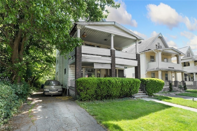 view of front facade with a front yard and a balcony