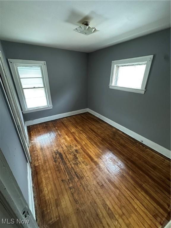 unfurnished room with baseboards and hardwood / wood-style floors