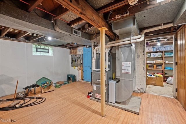 basement featuring hardwood / wood-style floors and heating unit