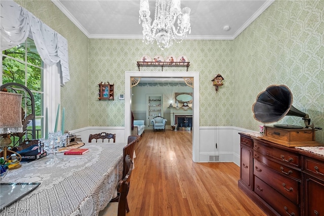 dining space with crown molding, an inviting chandelier, and light wood-type flooring