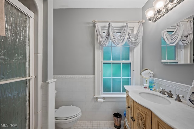 bathroom with tile walls, vanity, tile patterned floors, and toilet