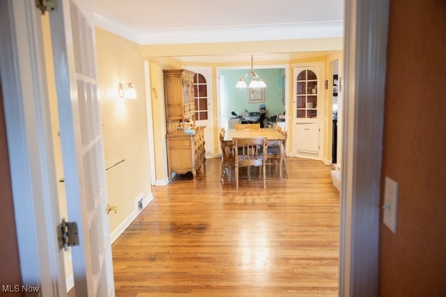 dining area featuring light wood-type flooring, an inviting chandelier, and ornamental molding