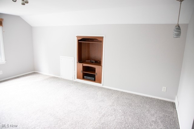 carpeted empty room featuring vaulted ceiling and built in features