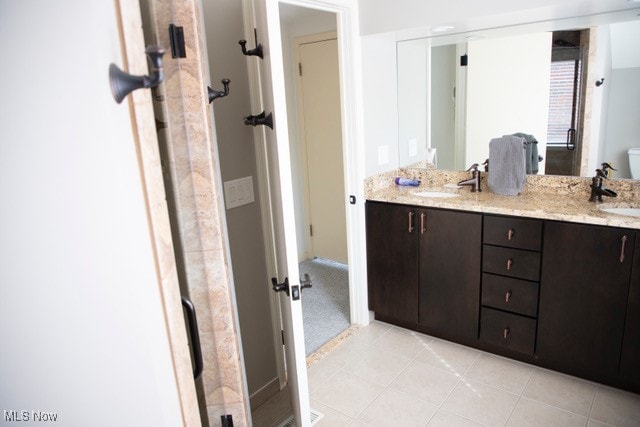 bathroom with toilet, vanity, and tile patterned floors