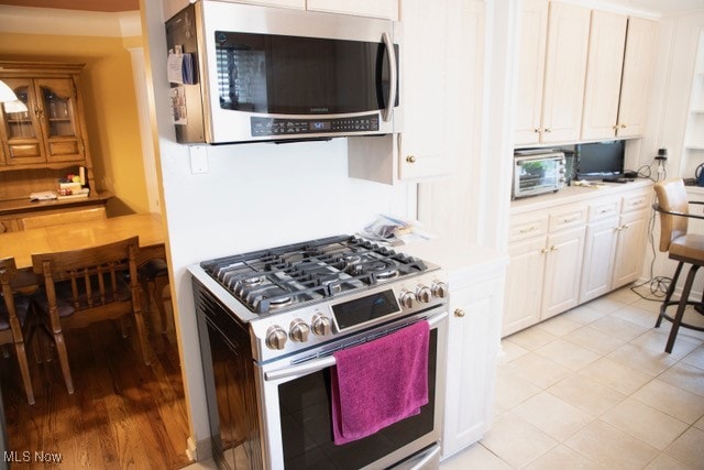 kitchen featuring white cabinets, appliances with stainless steel finishes, and light tile patterned flooring