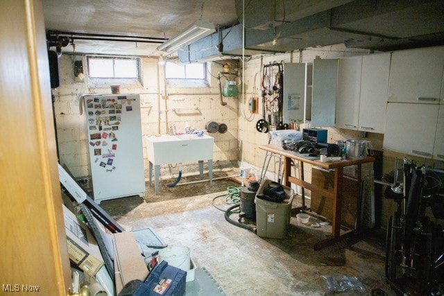 basement featuring sink and white fridge