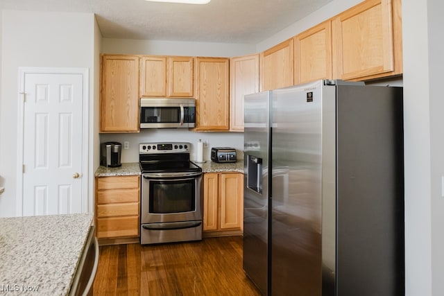 kitchen featuring light stone counters, a textured ceiling, stainless steel appliances, light brown cabinets, and dark hardwood / wood-style flooring