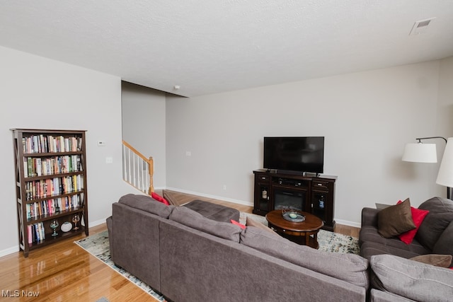 living room with a textured ceiling and light hardwood / wood-style flooring