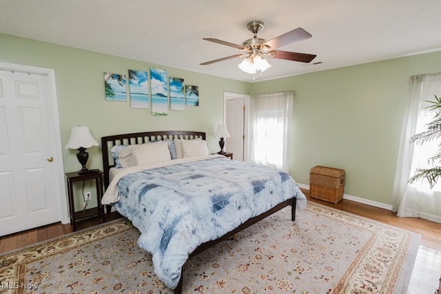 bedroom with ceiling fan, hardwood / wood-style flooring, and multiple windows