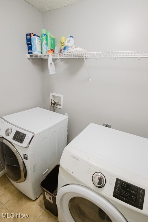 laundry area with independent washer and dryer and light tile patterned floors