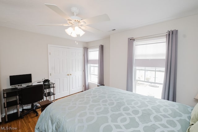 bedroom with dark wood-type flooring, ceiling fan, and a closet