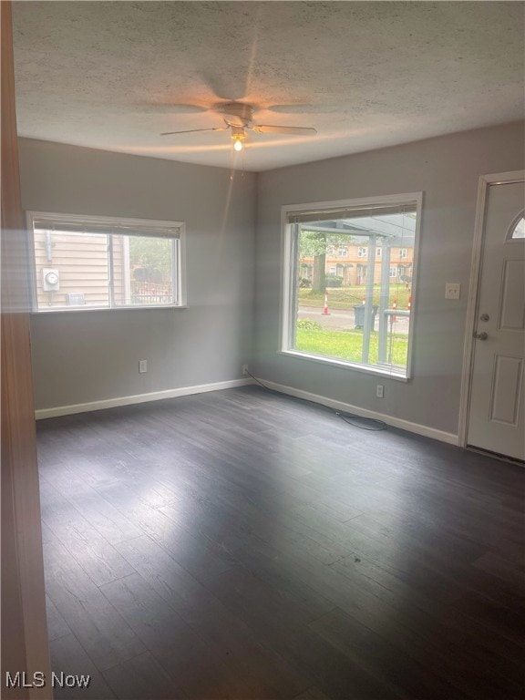 spare room with ceiling fan, dark wood-type flooring, and a textured ceiling