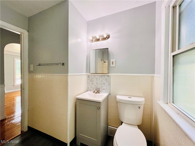 bathroom with tile walls, hardwood / wood-style flooring, vanity, and toilet