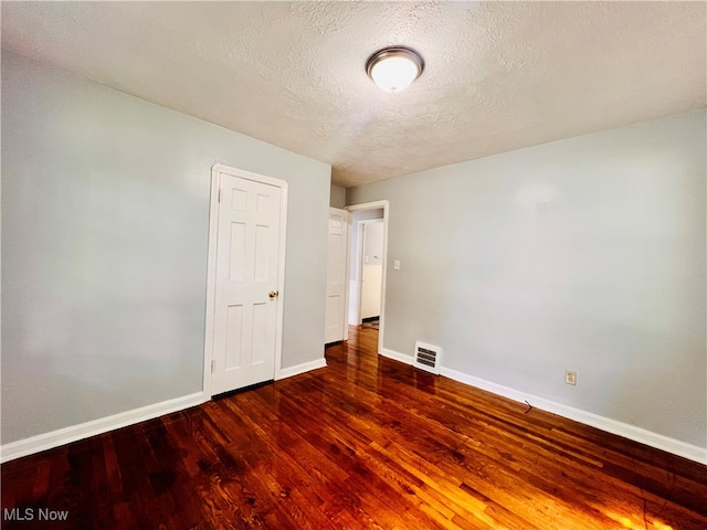 spare room with a textured ceiling and dark wood-type flooring