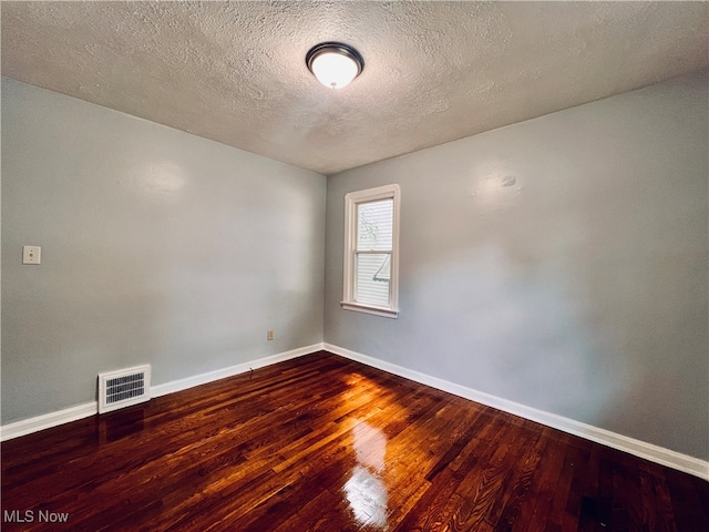 empty room with a textured ceiling and hardwood / wood-style flooring