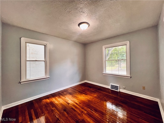 empty room with wood-type flooring and a textured ceiling