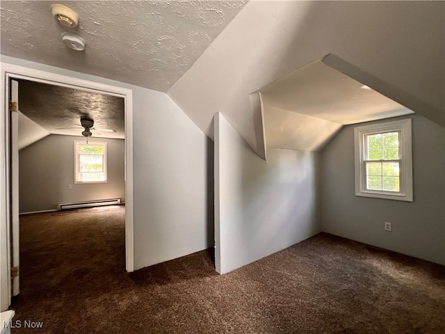 bonus room with a textured ceiling, lofted ceiling, a baseboard radiator, and dark colored carpet