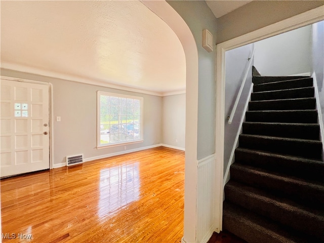 stairs featuring wood-type flooring and crown molding