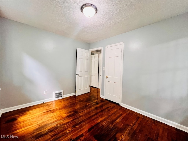 interior space featuring a textured ceiling and dark hardwood / wood-style flooring