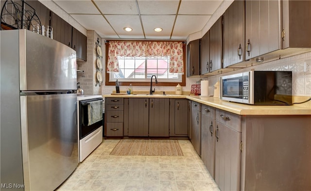 kitchen featuring a drop ceiling, stainless steel appliances, decorative backsplash, and sink